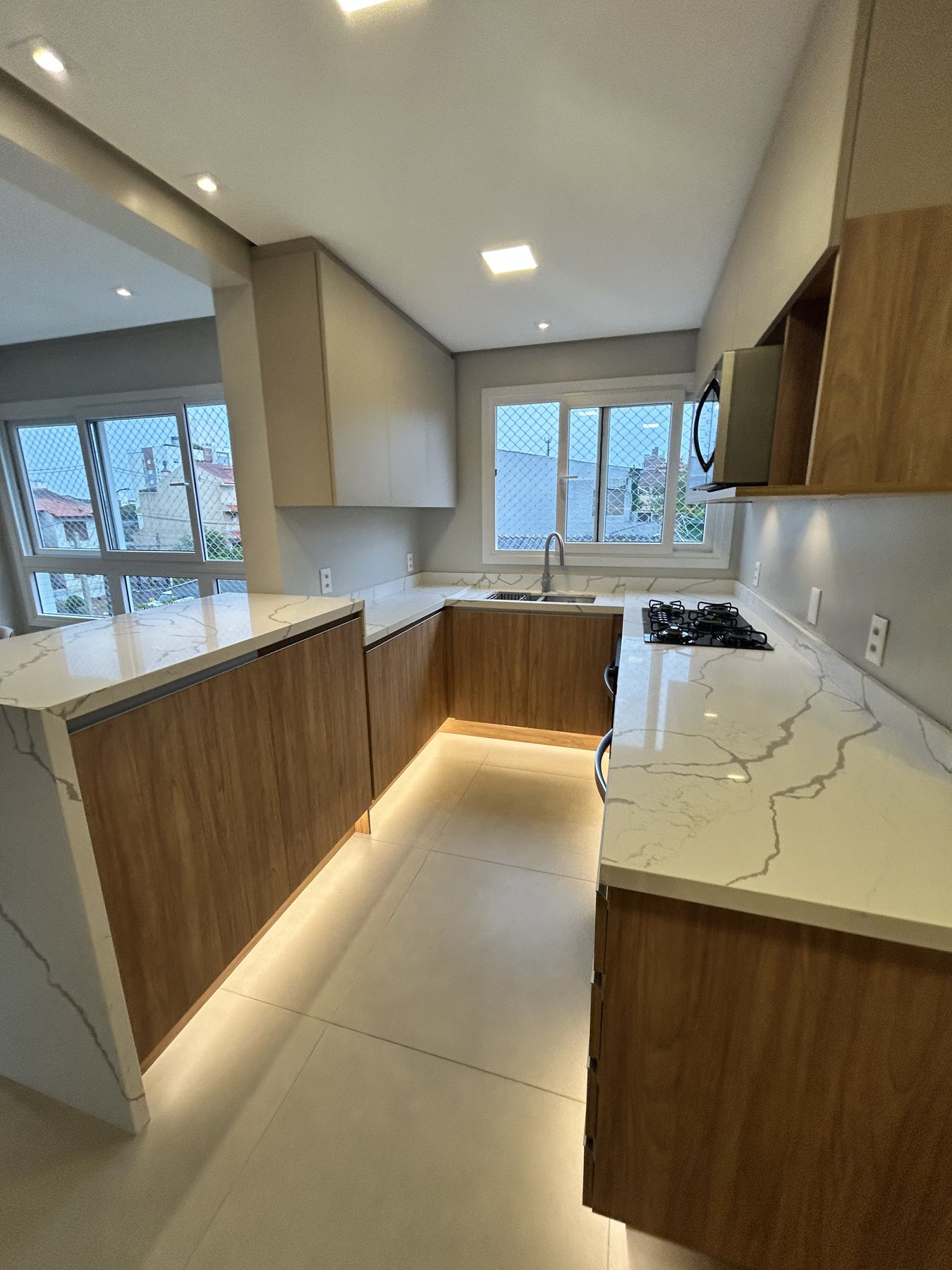 Cozinha em U com bancada em quartzo e marcenaria amadeirada